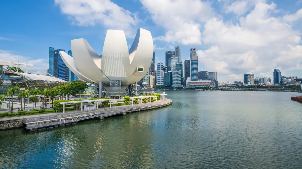 ArtScience Museum — The white lotus-petal ArtScience Museum in daylight beside Marina Bay, with the CBD skyline behind