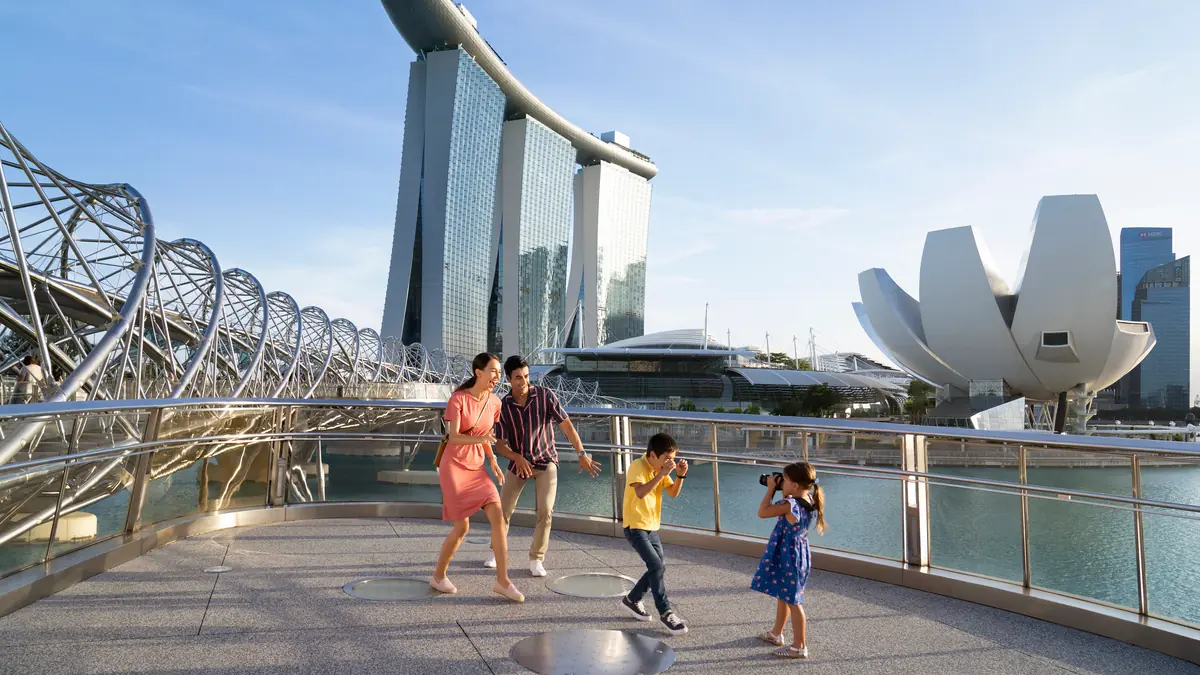 ArtScience Museum — A family taking photos on the Helix Bridge with the ArtScience Museum and Marina Bay Sands behind