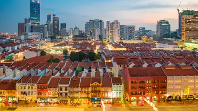 Chinatown — Red-tiled shophouse rooftops of Singapore's Chinatown at dusk with the CBD skyline behind