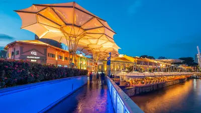 Clarke Quay — The Clarke Quay riverfront promenade lit up at blue hour, with canopies and waterside restaurants along the Singapore River