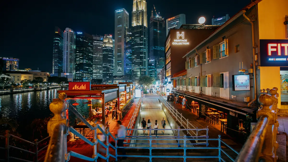 Clarke Quay — The riverside walkway at Boat Quay at night, lined with lit bars and restaurants below the CBD skyline
