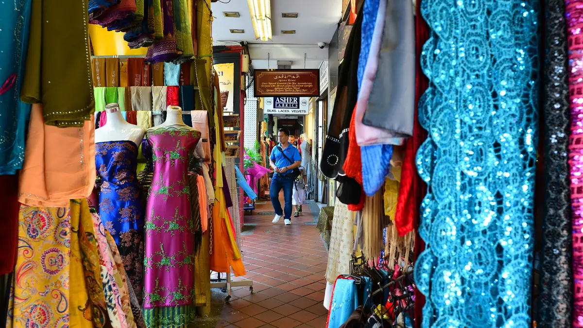 Bolts of brightly coloured fabric and traditional garments hanging outside a textile shop on Arab Street