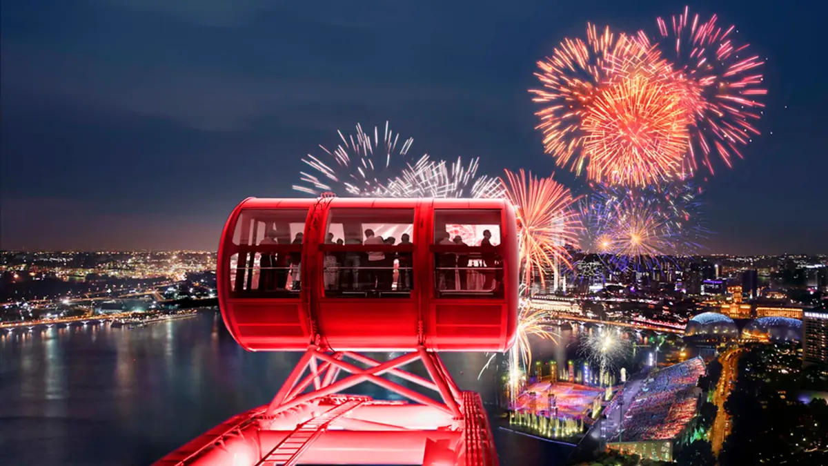 Singapore Flyer — Fireworks over Marina Bay behind a Singapore Flyer capsule lit pink at night
