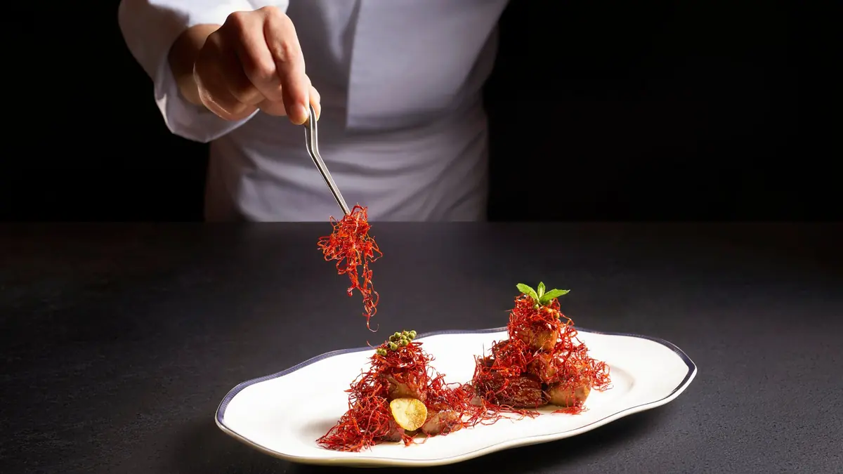 A chef plating a signature dish at Cherry Garden by Chef Fei, Singapore